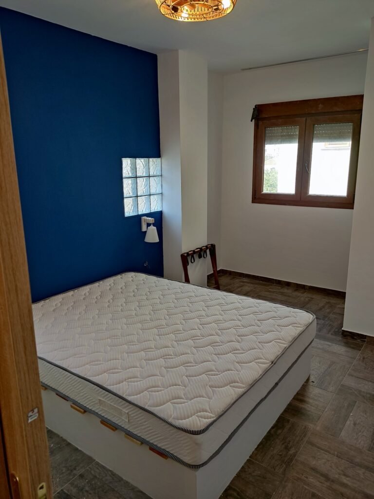 Υπνοδωμάτιο με μπλε τοίχο και λευκές επιφάνειες